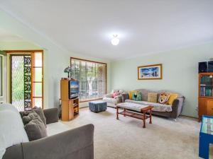 a living room with a couch and a tv at Peace by the Beach by Experience Jervis Bay in Vincentia