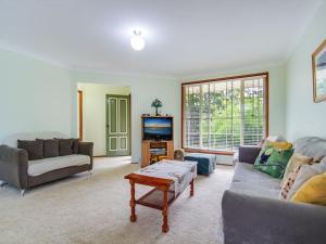 a living room with a couch and a tv at Peace by the Beach by Experience Jervis Bay in Vincentia