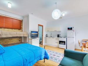 a bedroom with a blue bed and a kitchen at Peace by the Beach by Experience Jervis Bay in Vincentia