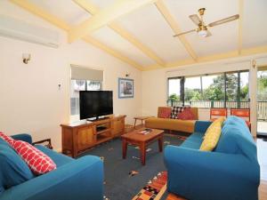 a living room with blue couches and a flat screen tv at Seaview by Experience Jervis Bay in Vincentia