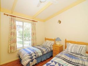 two beds in a bedroom with a window at Seaview by Experience Jervis Bay in Vincentia