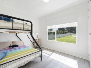 ein Schlafzimmer mit einem Etagenbett und einem Fenster in der Unterkunft Affordable Fully Renovated Cottage in St Georges Basin