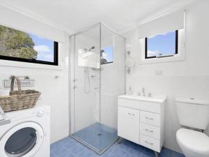 ein weißes Bad mit einem WC und einer Dusche in der Unterkunft Affordable Fully Renovated Cottage in St Georges Basin