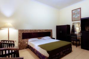 een slaapkamer met een bed, een bureau en een stoel bij Hotel Mahkota Plengkung by ecommerceloka in Banyuwangi