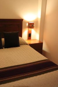 a bedroom with a bed with a night stand and a lamp at Casa Rafaela in Cusco
