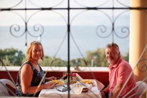 a man and a woman sitting at a table with food at Apraos Bay Hotel In Kalamaki Beach in Apraos