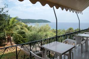 balcone con tavoli, sedie e vista sull'oceano di Apraos Bay Hotel In Kalamaki Beach ad Apraos