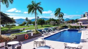 un complejo de piscina con mesas, sillas y palmeras en Cairns Harbourside Hotel, en Cairns