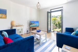 a living room with blue couches and a tv at 6 Oystercatcher Court - Stylish Apartment In Coastal Village Location in Stokeinteignhead