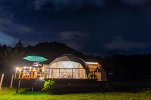 a yurt with an umbrella in a field at night at Glamping Claro de Luna in Guatavita