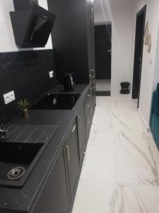 a black kitchen with a sink and a mirror at Apartament Królewiecka 22 Centrum Molo jezioro Czos in Mrągowo