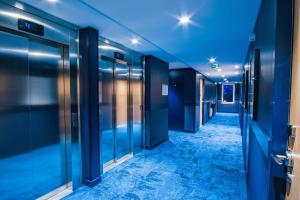a corridor of an office with blue walls and glass doors at ibis Styles Albertville in Albertville