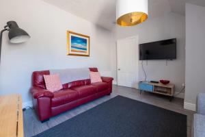 a red leather couch in a living room with a tv at Dryburgh Apartments No2 in Inverness