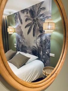 a mirror reflecting a bedroom with a bed and palm trees at Hôtel du Lion d'OR in Charolles