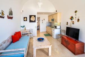 un soggiorno con divano blu e una cucina di Moschatos Beach House a Kamari