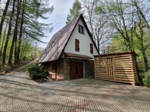 een huis met een gambrel dak en een garage bij Leśny Zakątek in Dębica