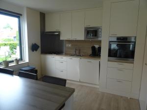 a kitchen with white cabinets and a table and a window at Kustverhuur, Park Schoneveld, Stern 234 met eigen elektrische laadpaal in Breskens