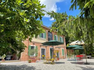 ein Gebäude mit Tischen und Sonnenschirmen davor in der Unterkunft Noi Due - Bed & Breakfast nel Monferrato in Quargnento