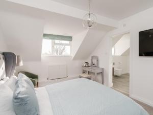 a white bedroom with a bed and a television at Pike and Eel Hotel and Marina in Needingworth