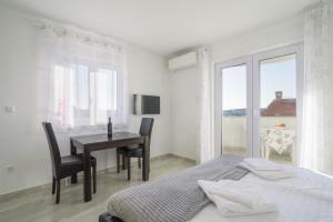 a white bedroom with a table and a bed and a window at Villa Anđelo in Trogir +39 photos