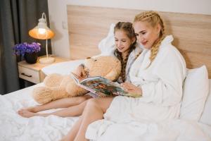 two girls in towels sitting on a bed reading a book at Nota Bene Loft in Lviv