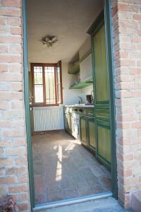 uma cozinha com armários verdes e uma parede de tijolos em La Casina em Casteggio
