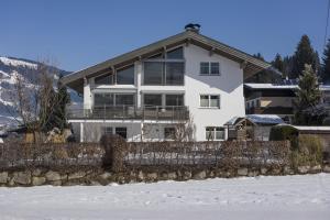 a white house with a fence in the snow at Appartement Ortner in Westendorf