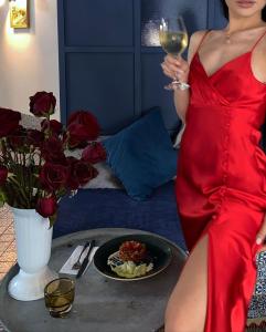 Villa Livia Boutique Apartments في رافدا: امرأة ترتدي ثوب احمر تحمل كوب من النبيذ