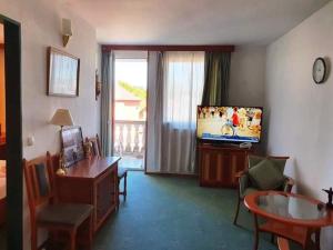 a living room with a desk and a table and a television at Palota Apartman in Hévíz