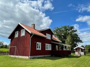 a red house with a red roof on a field at Humpen, Hultåkra in Mariannelund