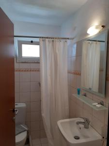 a bathroom with a white shower curtain and a sink at Hotel Strimoniko in Asprovalta