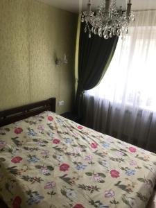 1 Schlafzimmer mit einem Bett mit Blumenbettdecke und einem Kronleuchter in der Unterkunft Апартаменты Ботанический Сад in Kiew