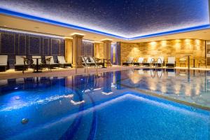 a pool in a hotel with chairs and tables at A Hoteli - Hotel Park in Vrnjačka Banja