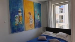 sypialnia z obrazami na ścianie i łóżkiem w obiekcie Impresja 42 Apartament z garażem w Kołobrzegu