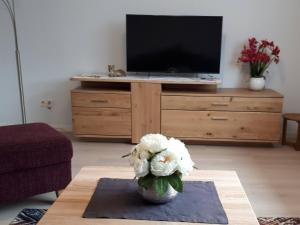 een woonkamer met een televisie en een vaas met bloemen bij Haus Marianne Schmelzle in Freudenstadt