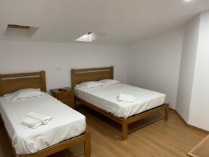 two beds in a room with white sheets and towels at Kualquer Koisa in Tondela