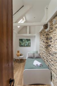 Habitación con cama y pared de piedra. en Le Cerf Volant - une pépite à l'Intramuros en Saint-Malo