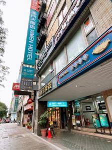 un edificio con letreros al lado de una calle en Ximen Hotel, en Taipéi