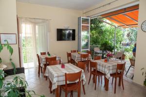 a restaurant with tables and chairs and a tv on the wall at Hotel Loula Rooms and Apartments in Kamena Vourla