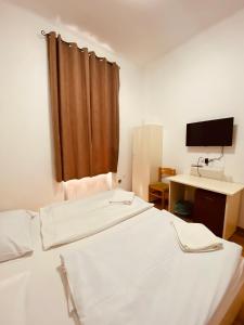 a room with two beds and a desk and a television at Easy Star Hotel in Budapest