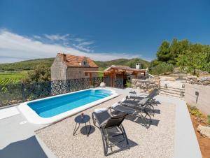 a swimming pool with chairs and a house at Stone House Prapatna in Smokvica