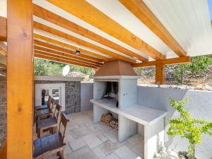 eine Außenküche mit einem Holzofen auf einer Terrasse in der Unterkunft Stone House Prapatna in Smokvica
