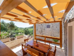 a patio with a wooden table and chairs on a balcony at Stone House Prapatna in Smokvica