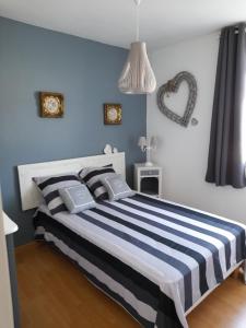 a bedroom with a bed with a blue and white striped bedspread at LA CLOSERIE D'ISABAULT in Eu