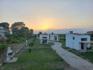 a row of white houses with the sunset in the background at KTIMA MORAITI - Seaside Houses in Katerini