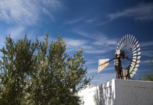 a windmill on top of a building with a blue sky at Dennehof Karoo Guesthouse in Prince Albert