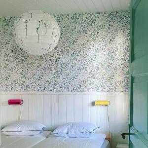 1 dormitorio con 1 cama y una pared con flores en Magnarp Strandbad, en Vejbystrand