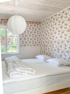 um quarto com uma cama branca e papel de parede floral em Magnarp Strandbad em Vejbystrand