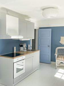 a kitchen with white cabinets and a blue wall at Magnarp Strandbad in Vejbystrand