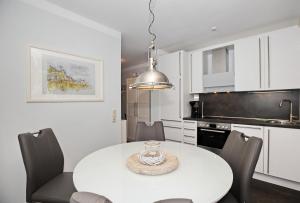 eine weiße Küche mit einem weißen Tisch und Stühlen in der Unterkunft Meeresblick Wohnung 104 - 4 Sterne DTV in Kühlungsborn